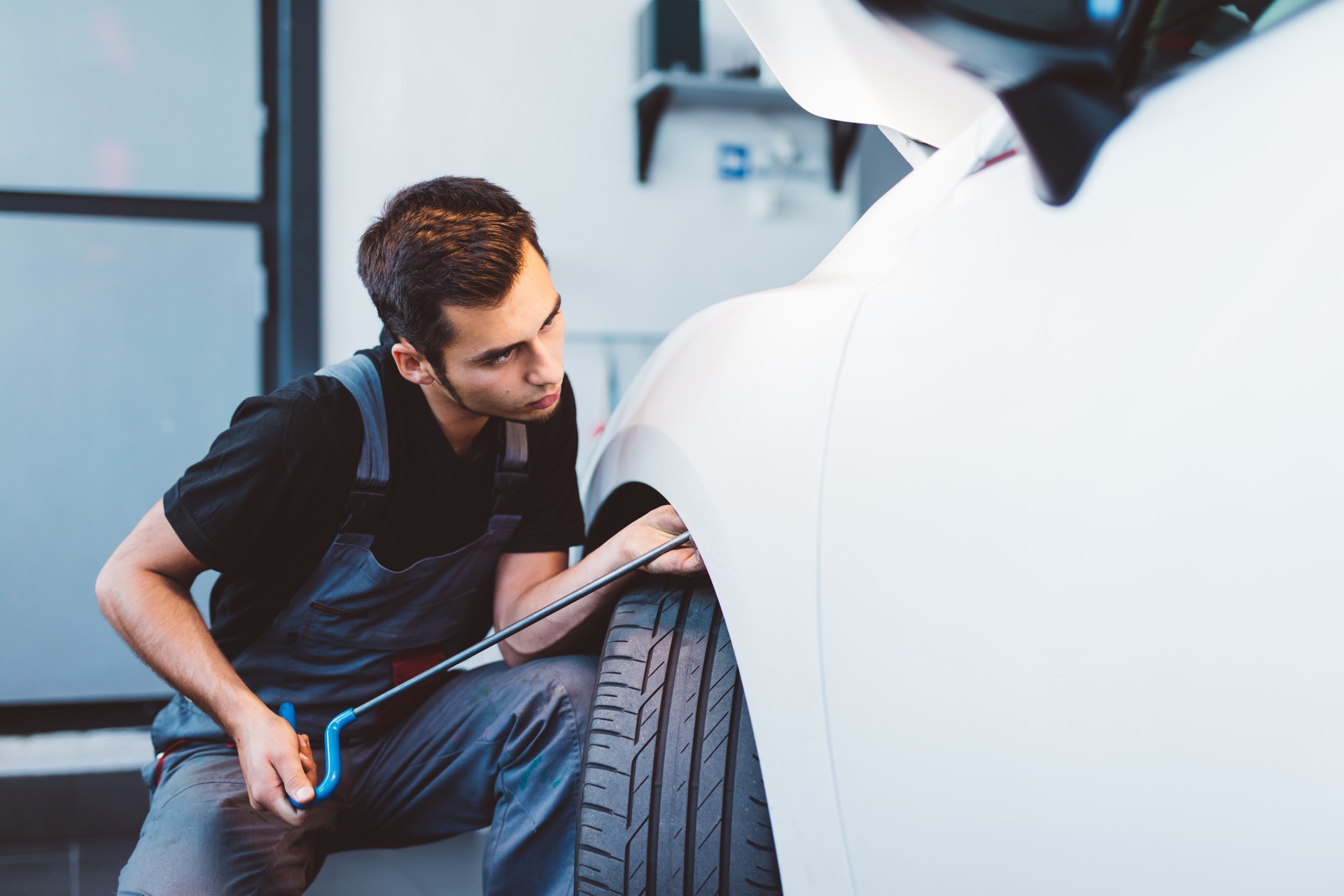 Car mechanic working to remove dent in workshop.